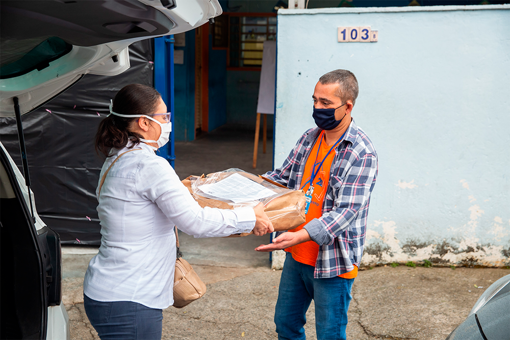 Luciana, dentista do OdontoSesc, entrega protetores a Humberto, do CAEI
